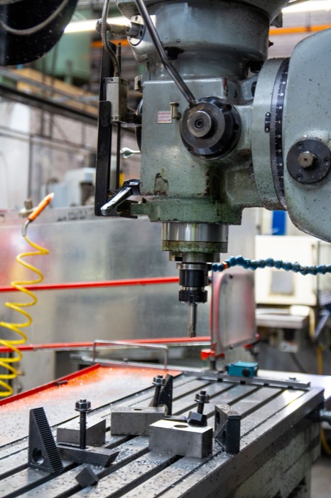 Vertical milling machine head with tooling above a clamped workpiece